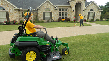 Grounds Guys mowing a lawn.